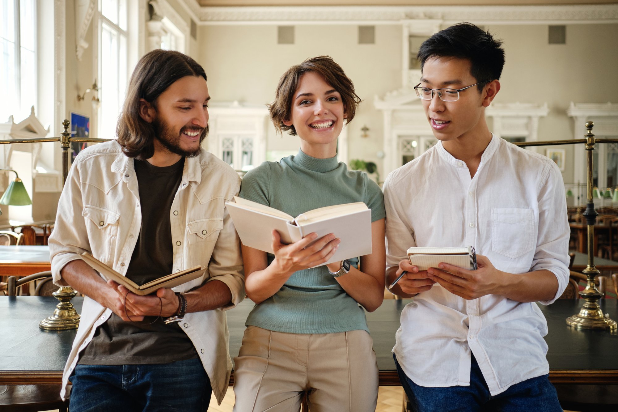 group-young-casual-multinational-students-joyfully-studying-with-book-making-notes-together-library-university